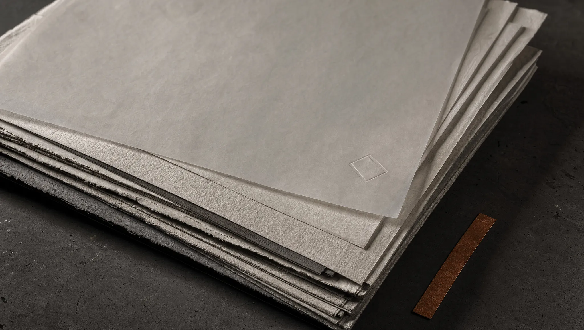 A stack of heavy uncoated paper sheets with a translucent vellum sheet on top